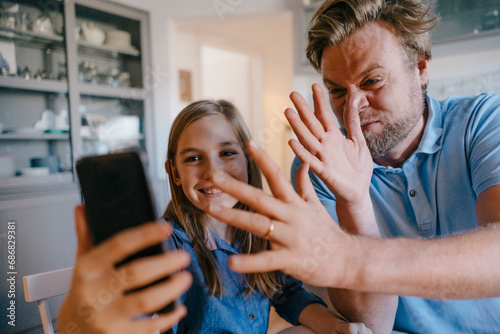 Playful father and daughter taking a selfie at home photo