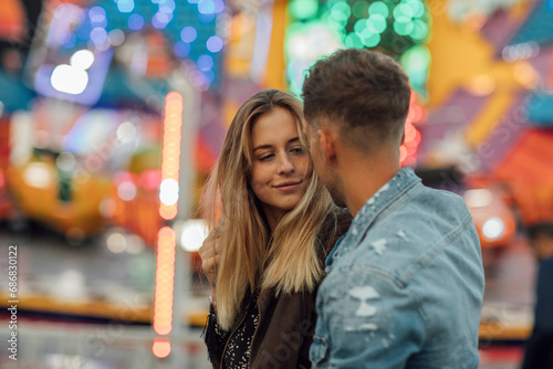 Young couple in love, embracing at a funfair