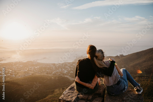 South Africa, Cape Town, Kloof Nek, two women sitting on rock at sunset