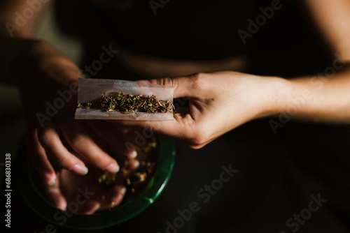 Young woman rolling a joint at home