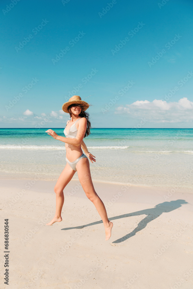 Spain, Mallorca, Happy young woman on holidays jumping on the beach during a summer day
