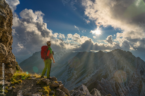 Italy, Veneto, Dolomites, Alta Via Bepi Zac, mountaineer standing on Costabella mountain at sunset