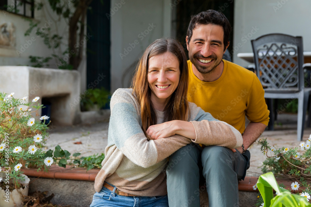 Smiling couple sitting on steps against farmhouse Smiling couple sitting on steps against farmhouse