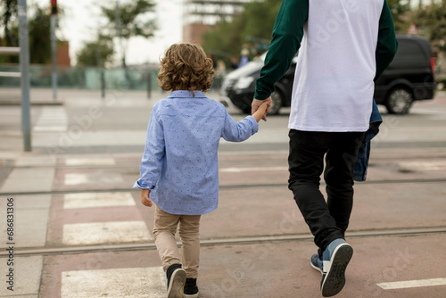 Rear view of father and son walking hand in hand in the city photo