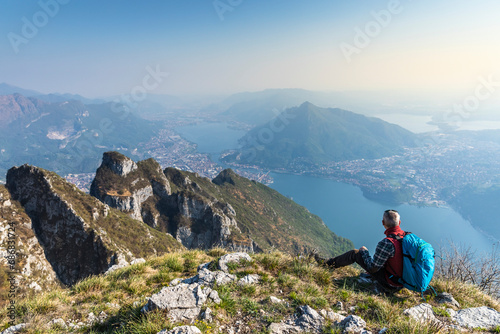 Rear view of hiker sitting on mountaintop, Orobie Alps, Lecco, Italy