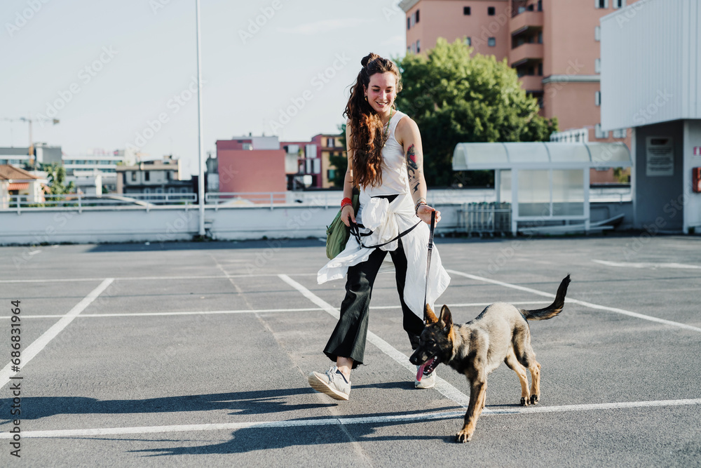 Naklejka premium Woman walking with dog in parking lot