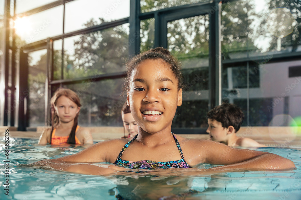 Portrait of smiling girl with friends in indoor swimming pool