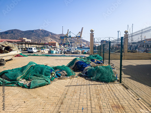 The view from behind the fence to the fishing port, where there are nets, boats and yachts