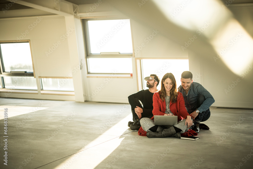 Colleagues sitting on floor of empty office rooms, making plans, using laptop and VR goggles Colleagues sitting on floor of empty office rooms, making plans, using laptop and VR goggles