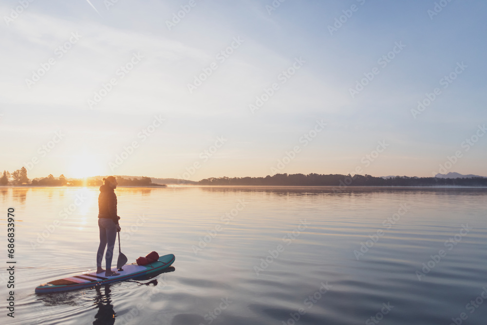Woman standing on sup board in the morning on a lake, Germany