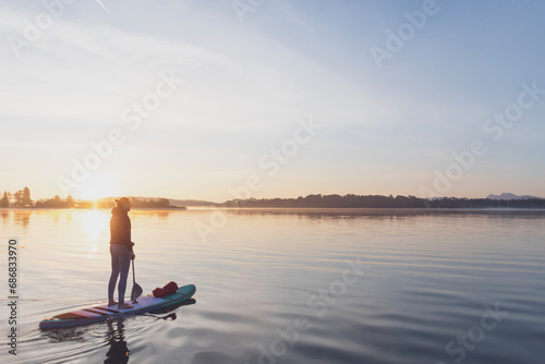 Woman standing on sup board in the morning on a lake, Germany