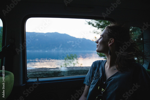 Young woman sitting on backseat in a car looking out of window © tunedin