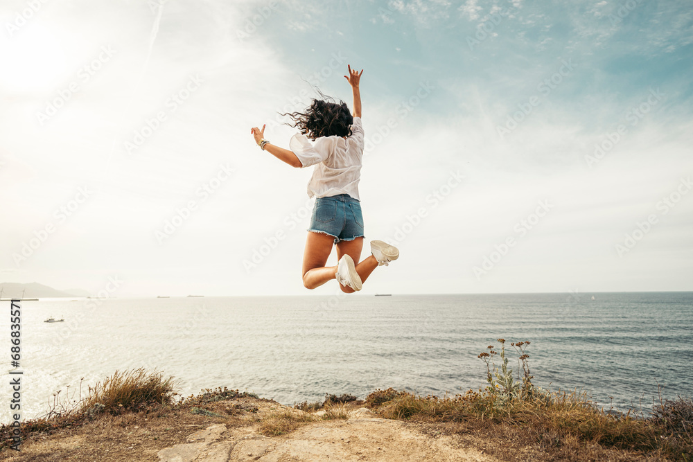 Rear view of yung woman jumping on viewpoint, Getxo, Spain Rear view of yung woman jumping on viewpoint, Getxo, Spain