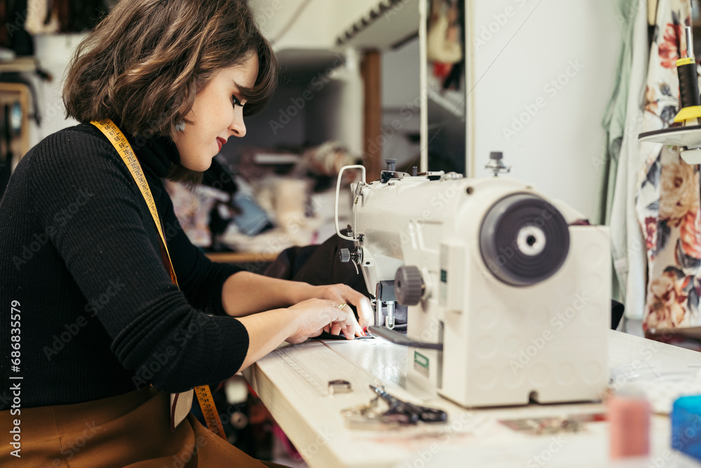 Young fashion designer using sewing machine
