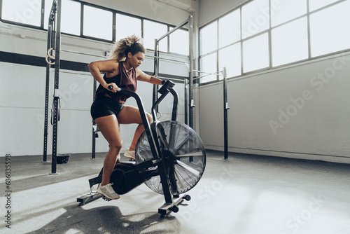 Young woman doing air bike workout in gym photo