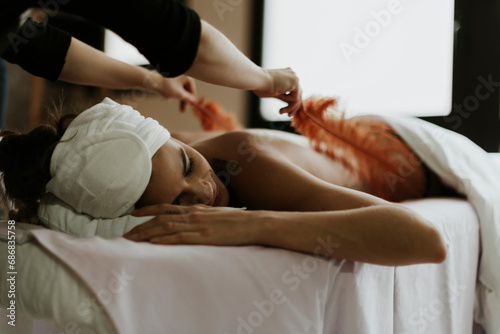 Young woman receiving a massage with feathers in a spa
