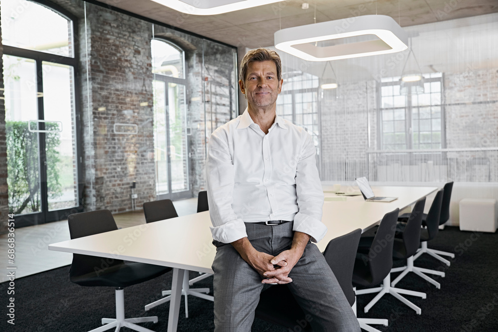 Portrait of confident mature businessman in conference room of modern office