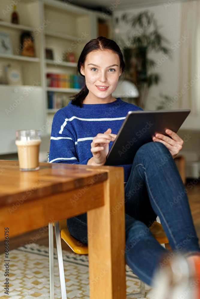 Young woman sitting at home, using digital tablet Young woman sitting at home, using digital tablet