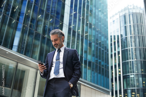 Obraz na płótnie Businessman using mobile phone outside office building in city w salonie