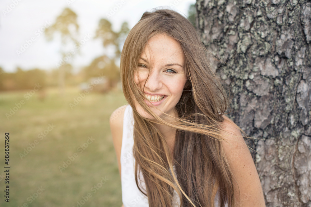 Portrait of laughing young woman leaning against tree trunk Portrait of laughing young woman leaning against tree trunk