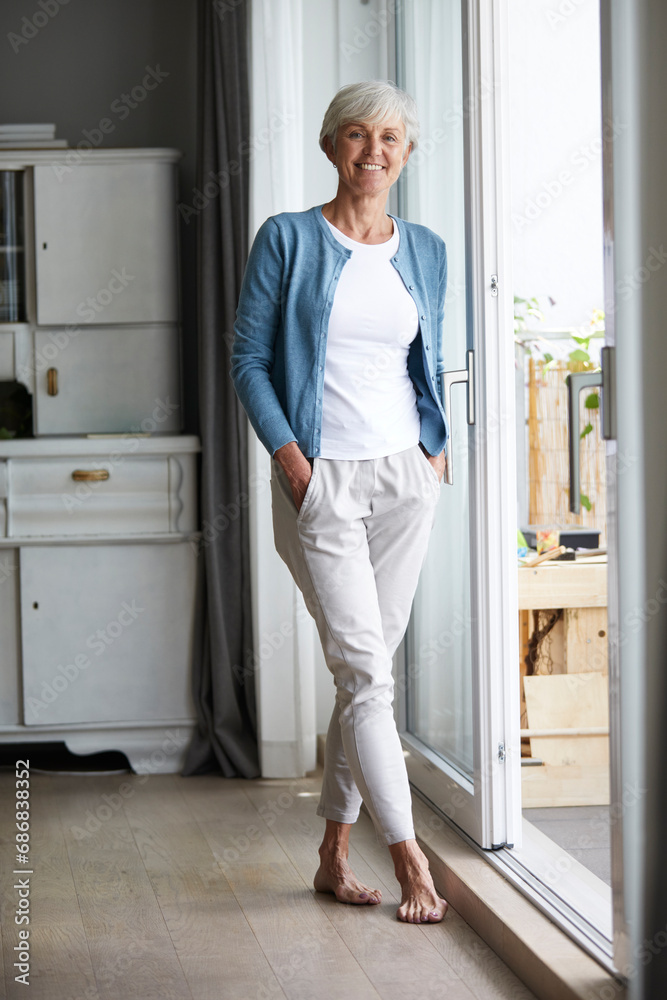 Senior woman standing with hands in pockets at home