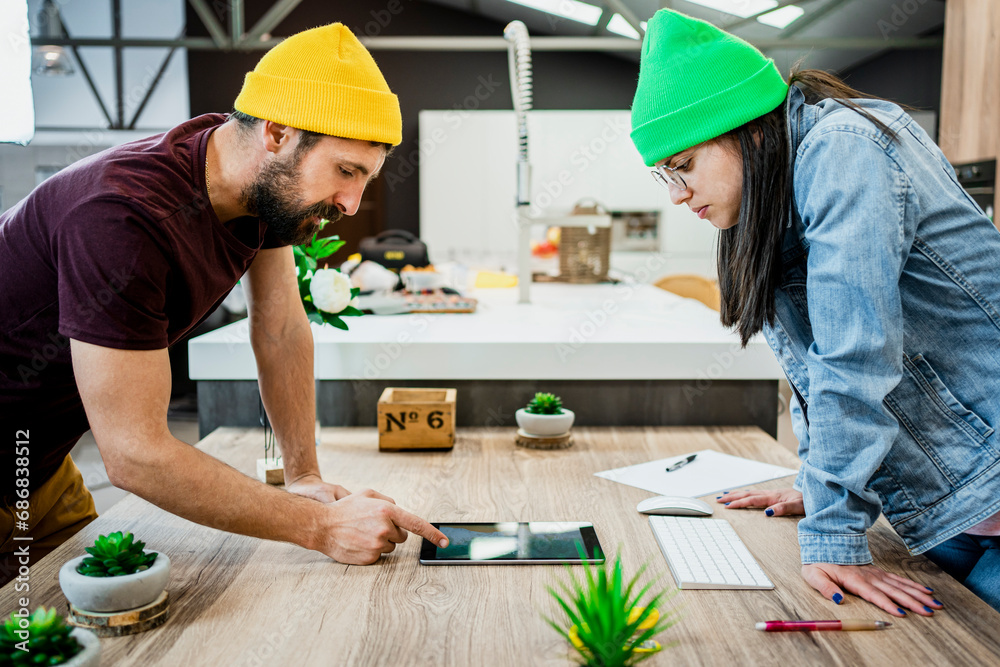 Business couple using digital tablet while bending over desk in modern office Business couple using digital tablet while bending over desk in modern office