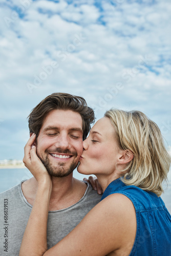 Happy young couple kissing on the beach