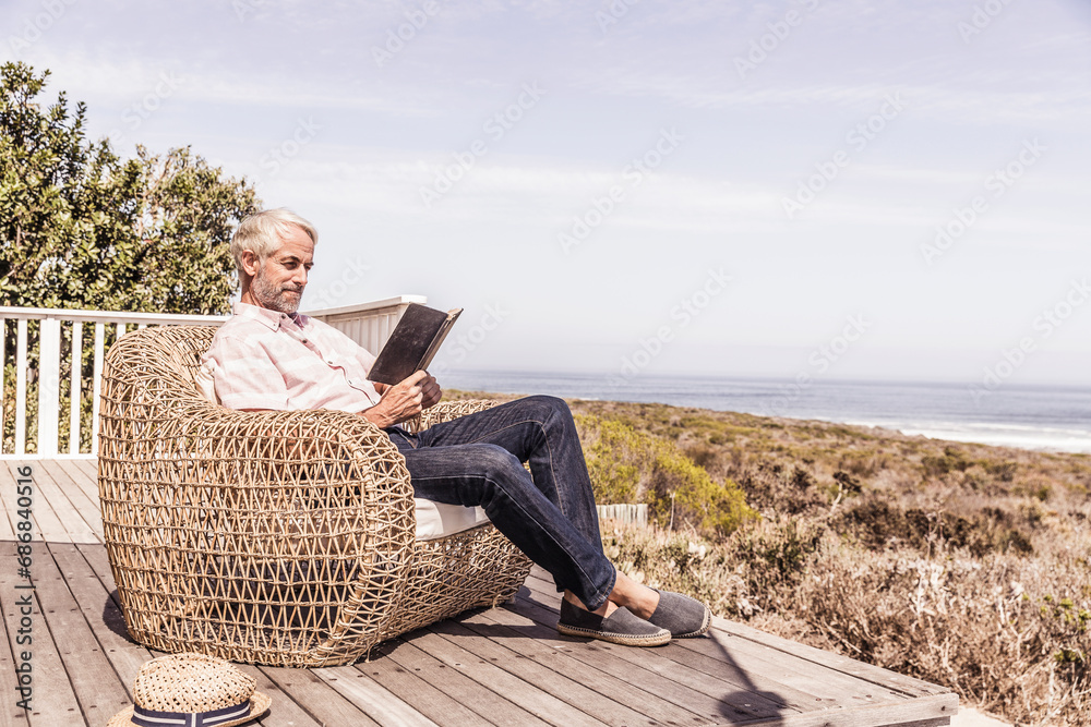 Man reading a book on a deck at the coast