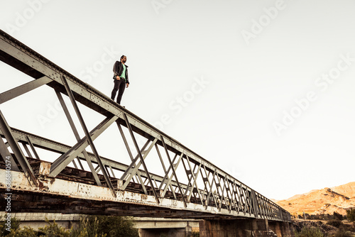 Man standing on metal bar of an old railway bridge © tunedin