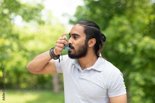 Young man in nature using asthma inhaler photo