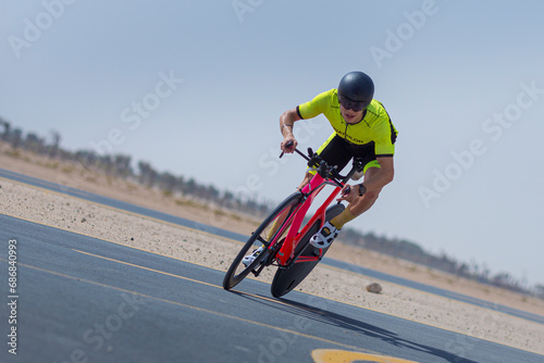 Determined cyclist riding bicycle on road against clear blue sky at desert in Dubai, United Arab Emirates photo