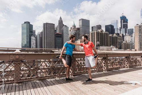 USA, New York City, two athletes stretching on Brooklyn Brige