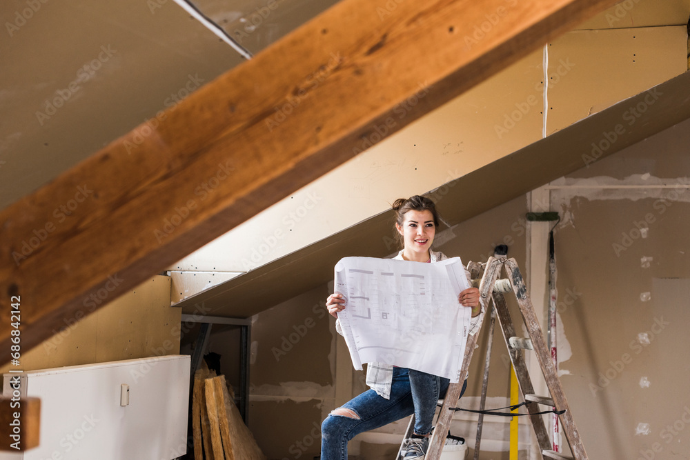 Young woman renovating her new home, holding construction plan Young woman renovating her new home, holding construction plan
