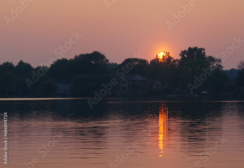 Canvas Print Setting sun overlooks still water of a Lake Wilcox reflecting orange sunset sun