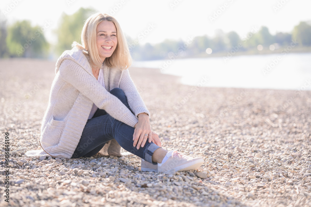 Happy mature woman sitting at the riverside