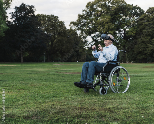 Senior man sitting in wheelchair in a park using Virtual Reality Glasses
