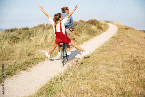 Obraz na płótnie Carefree girlfriend enjoying bicycle ride with boyfriend on sunny day w salonie