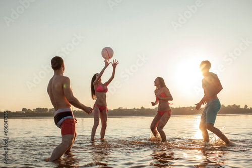 Happy friends playing with a ball in water