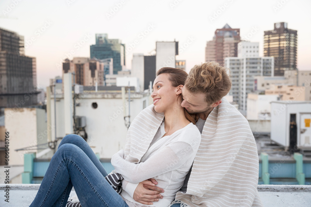 Romantic couple sitting on rooftop terrace, enjoying the view
