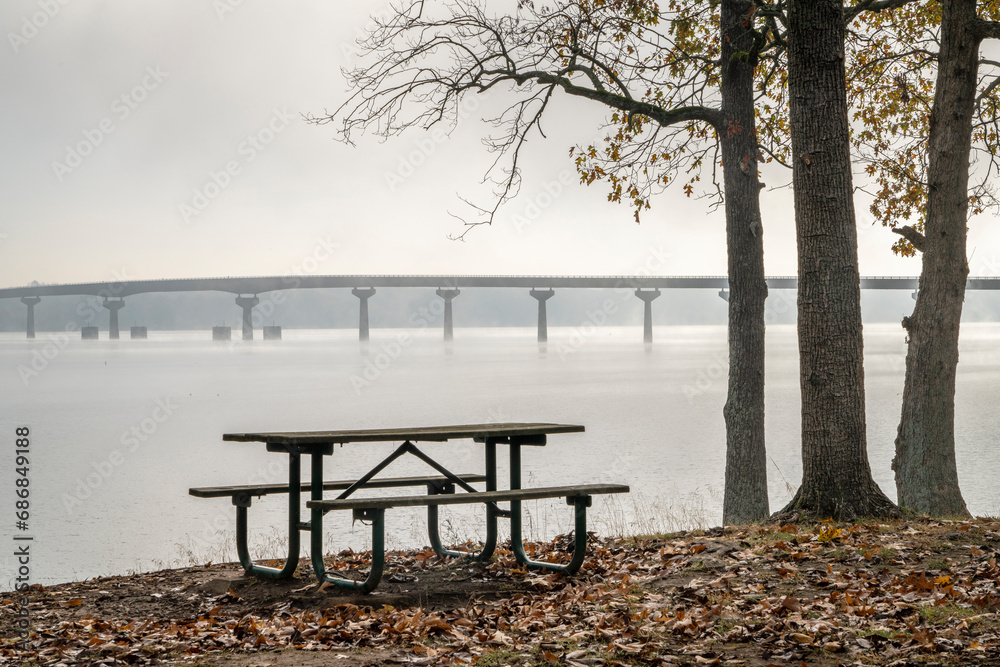 picnic table at Colbert Ferry Park, Natchez Trace Parkway with a view of the bridge over Tennessee River from Tennessee to Alabama, foggy November morning
