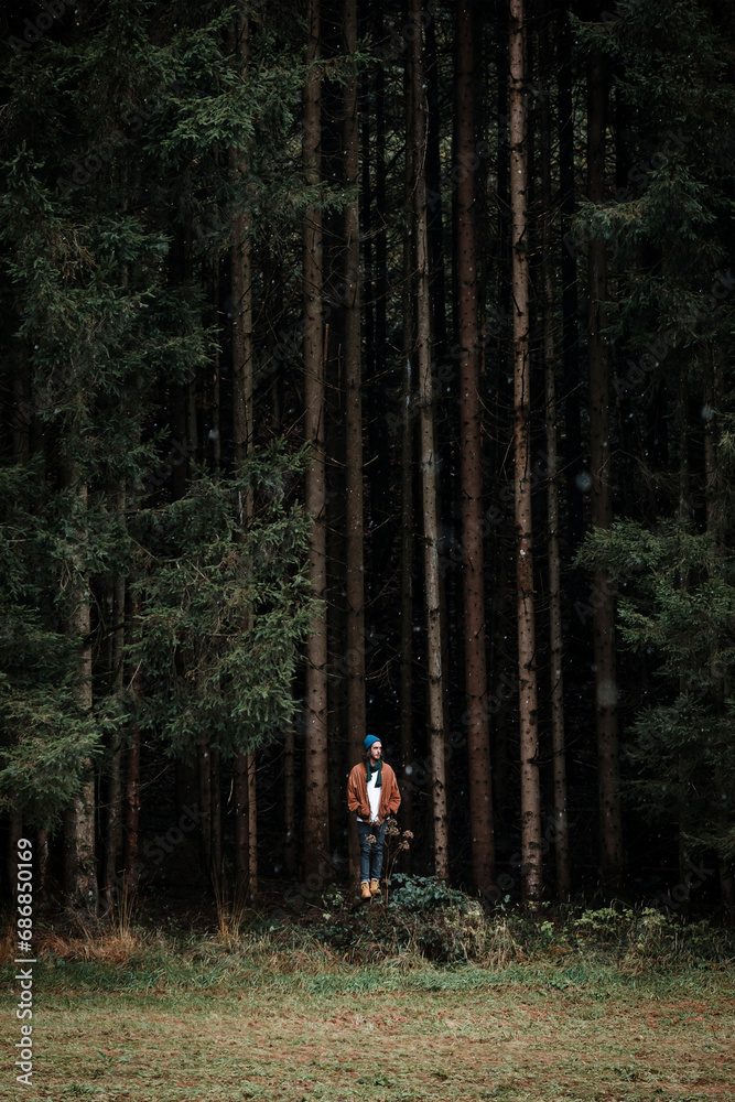 Young man standing in front of coniferous forest Young man standing in front of coniferous forest