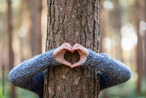 Woman embracing tree and making heart shape in Cannock Chase forest photo