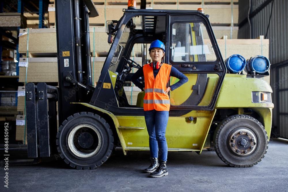 Portrait of confident female worker at forklift in factory