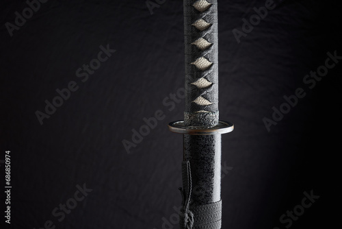Horizontal photo of sheathed katana with details of the handle and sheath, traditional Japanese sword isolated on black background photo