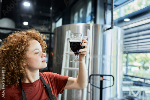 Woman working in craft brewery checking quality of a beer photo