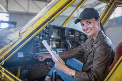 Female pilot inspecting light aircraft cockpit