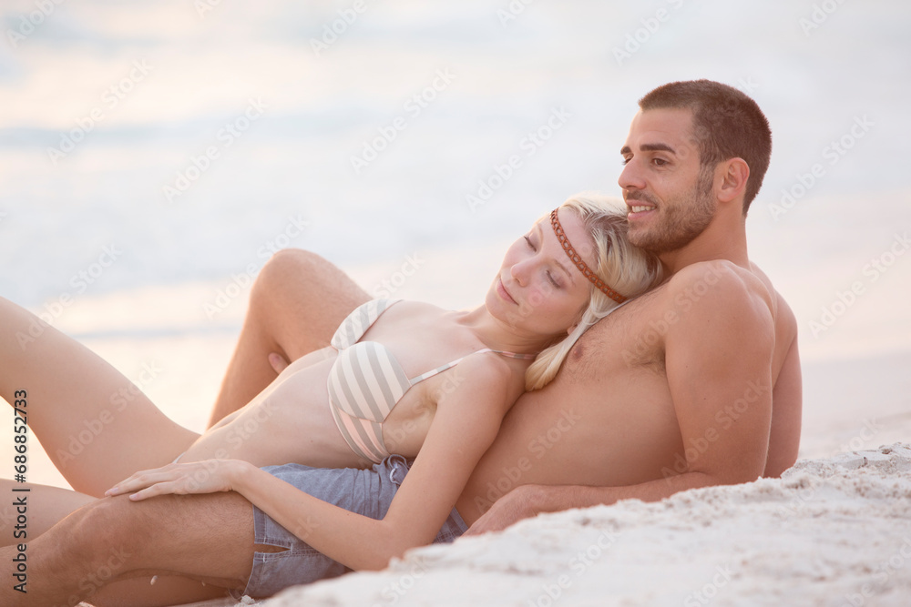 Young couple sitting on the beach, embracing Young couple sitting on the beach, embracing