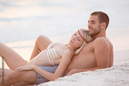 Young couple sitting on the beach, embracing