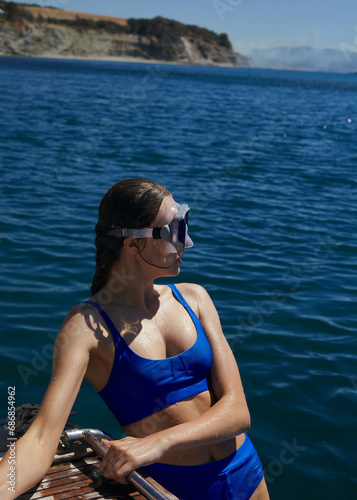 A beautiful woman in a blue swimsuit is relaxing at the sea enjoying her vacation