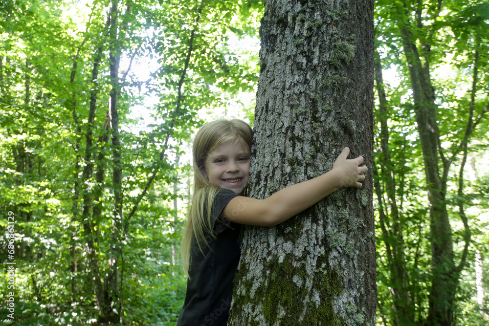Cute little girl hugging tree. Hugging and touching trees provide rich sensory experience for children, reduce stress, improve immunity, lower blood pressure, accelerate recovery from trauma Cute little girl hugging tree. Hugging and touching trees provide rich sensory experience for children, reduce stress, improve immunity, lower blood pressure, accelerate recovery from trauma